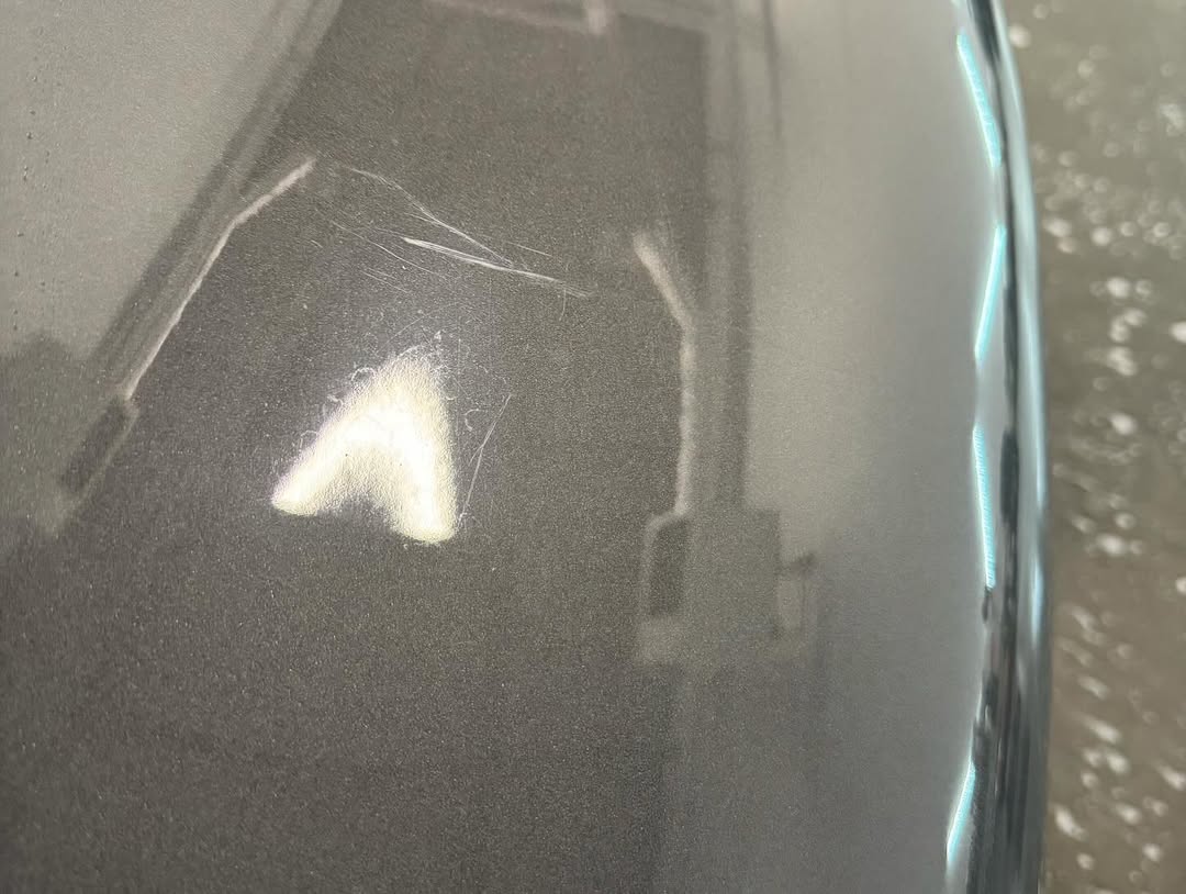 Porsche 911 Turbo panel before correction. Visible scratches and swirl marks under shop lighting.